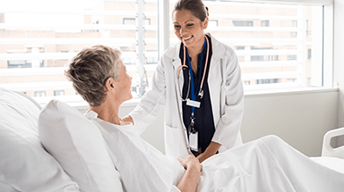 Female doctor talking to female patient in hospital bed