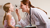Woman doctor looking into girl's mouth