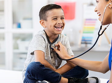 Doctor listening to a boy's heart with a stethoscope.