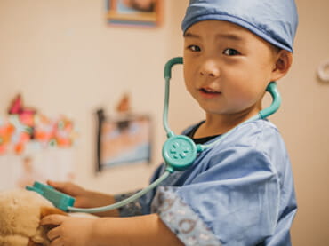 Child in scrubs with a toy stethoscope