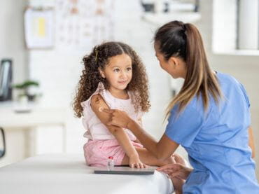 Provider putting a Bandaid on a girl's arm after a vaccination