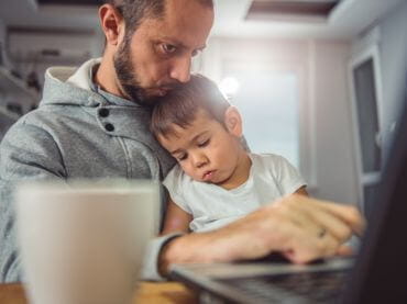 Father on laptop with child sitting in his lap