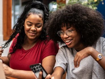 Two older teens looking at a cell phone