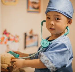 Young boy dressed up in scrubs like a doctor