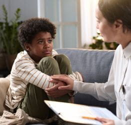 Young boy looking sad and talking to a doctor who is consoling him