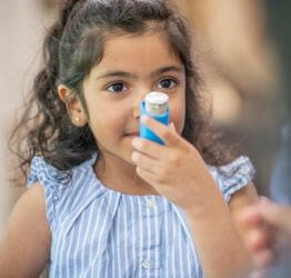 Girl holding an inhaler to her mouth