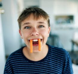 Boy with carrots in his mouth like fangs