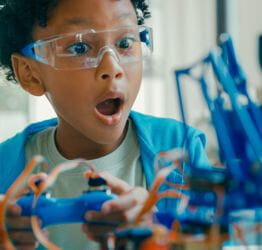 Child with safety glasses holding a remote control