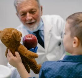 Doctor talking to a boy holding a teddy bear