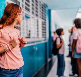 Girl standing alone looking at a group of kids