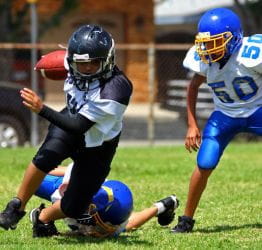 Children playing football in full uniform with helmets