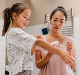 Mom putting lotion on girl's arm