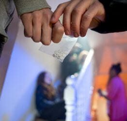 Two people passing a baggie of pills