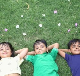 Three kids laying in the grass