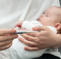 Parent holding an infant and a thermometer