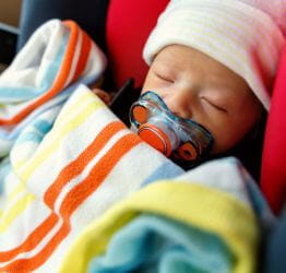 Infant in a car seat covered with a blanket