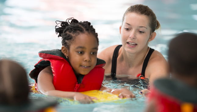 Girl with life jacket getting a swim lesson