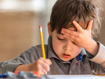 Boy doing schoolwork with his head in his hand