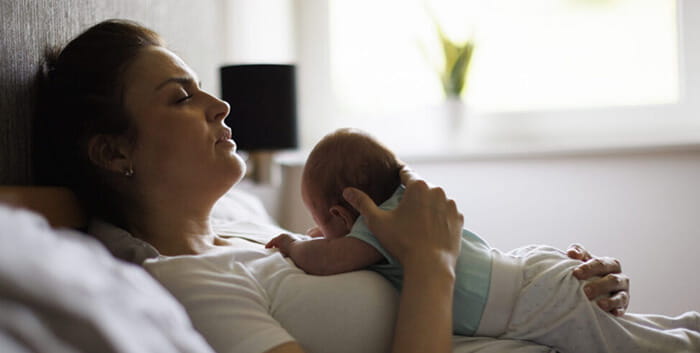 Mom lying in bed holding a baby on her chest
