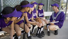 Coach talking to girls softball team on the bench