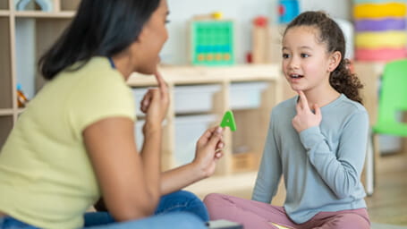 A young girl and her therapist engaging in speech therapy