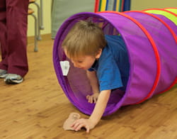 Child at the Center for Independence crawling through a tunnel.