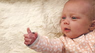 Baby lying on a blanket pointing