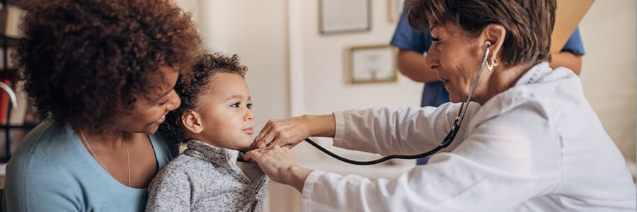 Mom holding baby while doctor listens to his heartbeat with a stethoscope