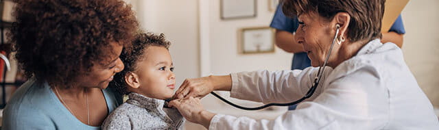 Mom holding baby while doctor listens to his heartbeat with a stethoscope