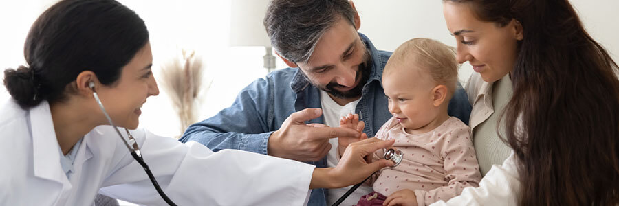 Parents holding their baby while a doctor listens to heartbeat with a stethoscope