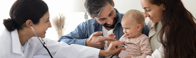 Parents holding their baby while a doctor listens to heartbeat with a stethoscope