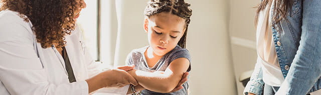 Doctor looking at young girls upper arm