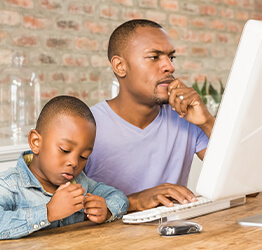 Man and son sitting at a desktop computer