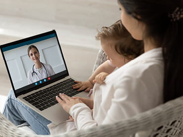 Mother and son at home talking to a doctor through an iPad.