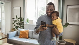 A father holding his son and scheduling an appointment on his phone