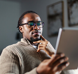 Man holding a tablet and looking at it thoughtfully