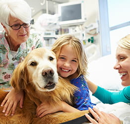 Young girl in a hospital hugging a golden retreiver