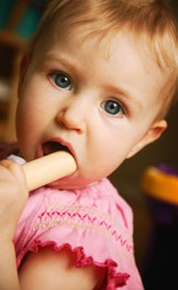 Girl toddler putting a toy block in her mouth