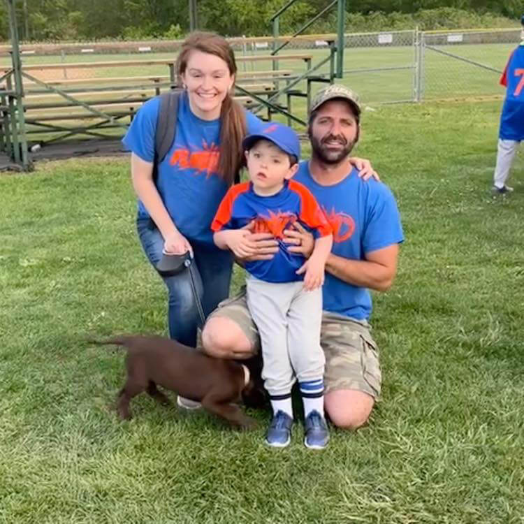 Dominic Yenzi with his parents in a baseball uniform