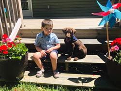 Dominic Yenzi sitting on the porch with a puppy