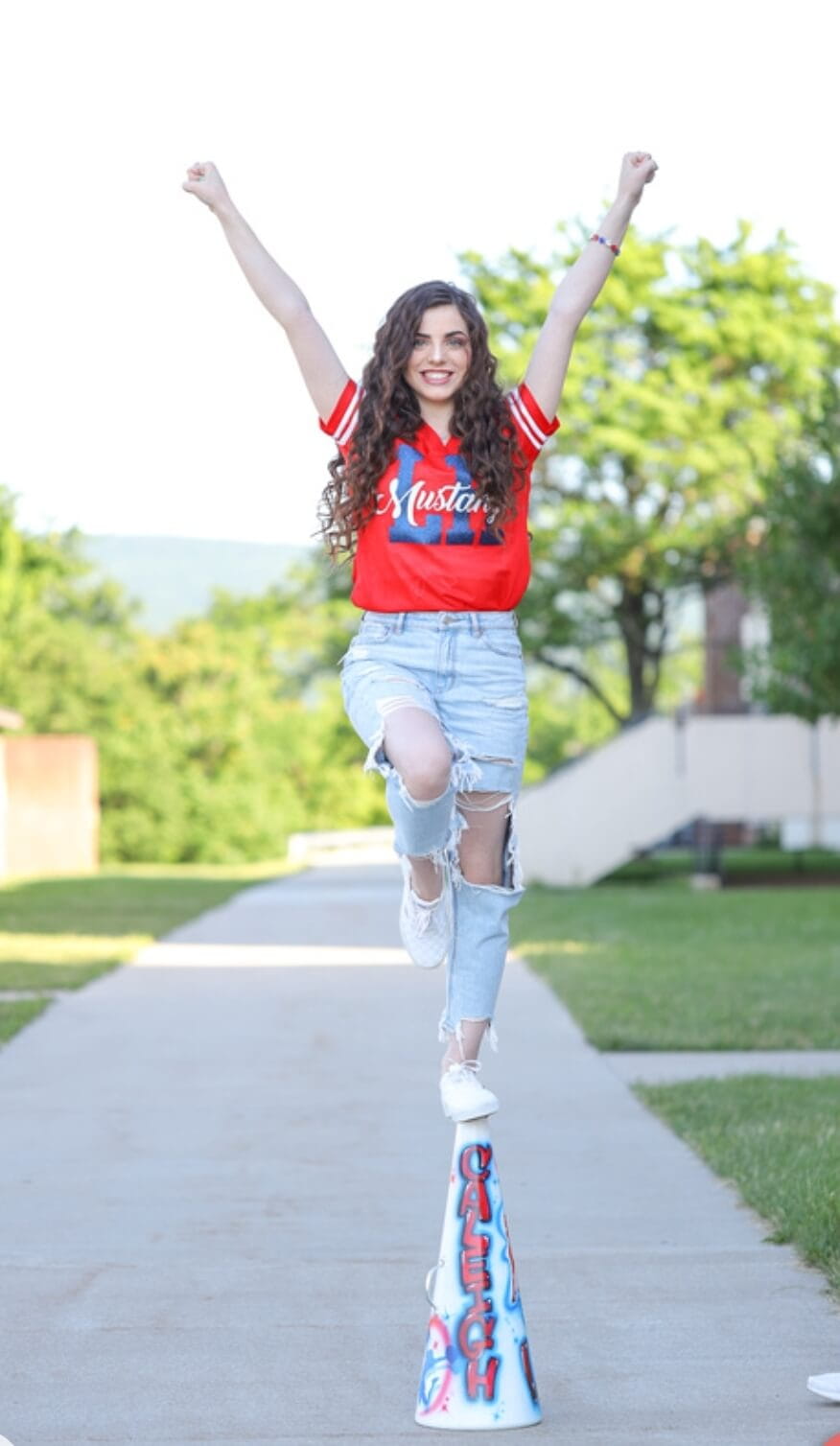 Caleigh McLay standing on a cheer megaphone with her arms in the air