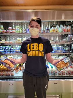 Casey wearing a shirt that says "LEBO SWIMMING" and holding food