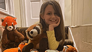 A young girl named Luella sitting in front of her collection of Red Panda stuffed animals