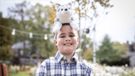 Miles smiling and posing with his stuffed dog Silvie on his head
