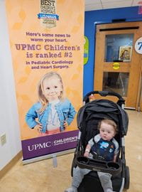 Matthias in a stroller in front of a sign for UPMC Children's Hospital of Pittsburgh.