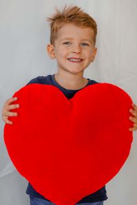 Tiago Maljacek Silva smiling and holding a big red heart decoration