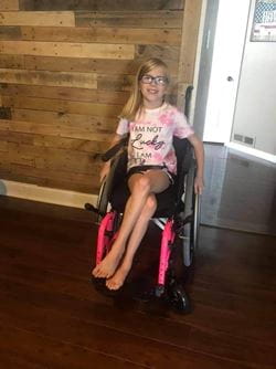 Kailynn McNally wearing a pink tie dye shirt and seated in a wheelchair