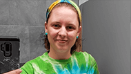 Mindy Nicholas taking a mirror selfie in a blue and green tye-dye shirt