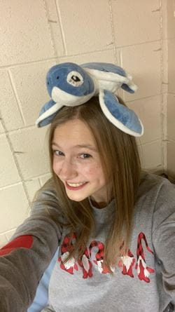 Anna Fleming with a blue and white turle stuffed animal balanced on her head
