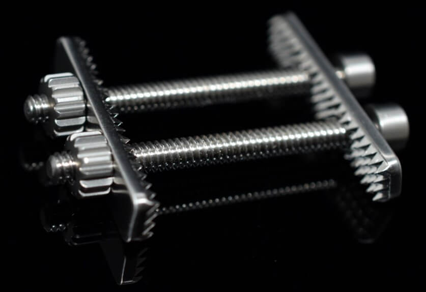 Two plates with aggressive teeth are maintained with two bolts and two nuts that secure the tendon grafts against bone.